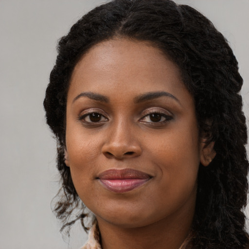 Joyful black young-adult female with long  black hair and brown eyes