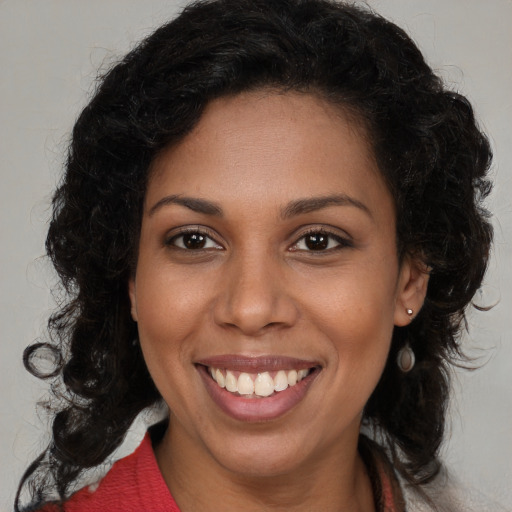 Joyful black young-adult female with long  brown hair and brown eyes