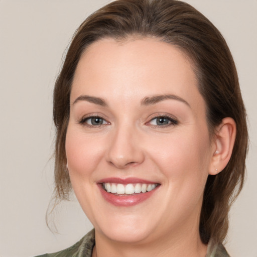 Joyful white young-adult female with medium  brown hair and grey eyes