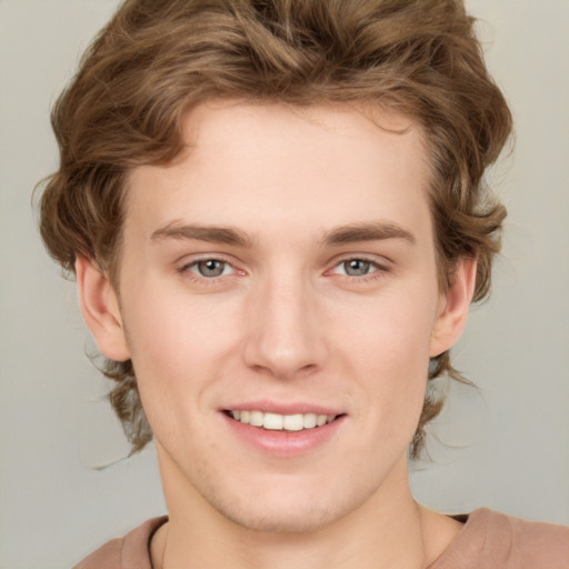 Joyful white young-adult male with medium  brown hair and grey eyes