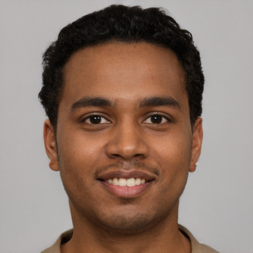 Joyful black young-adult male with short  brown hair and brown eyes