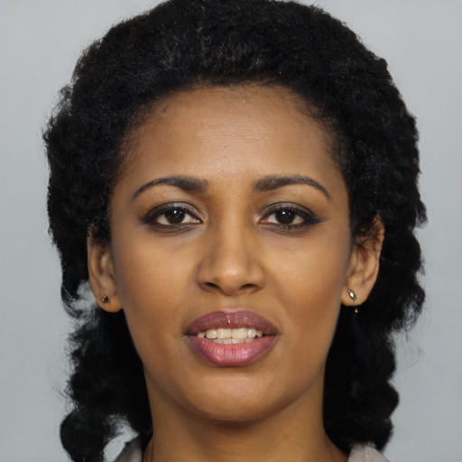 Joyful black young-adult female with long  black hair and brown eyes