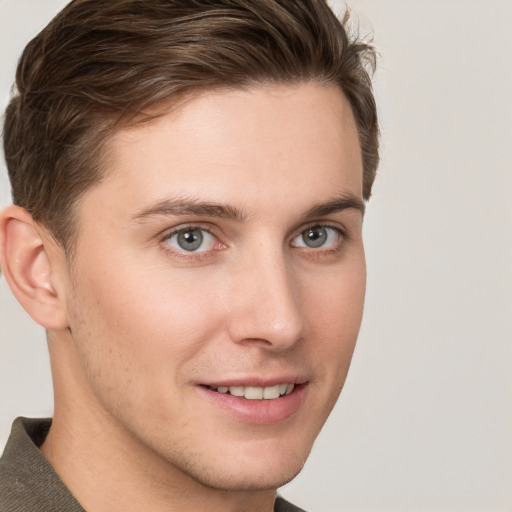 Joyful white young-adult male with short  brown hair and grey eyes