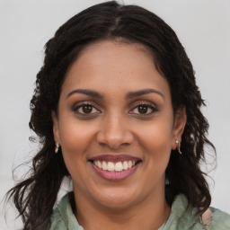 Joyful black young-adult female with long  brown hair and brown eyes