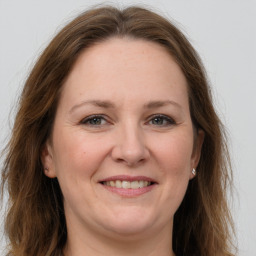 Joyful white adult female with long  brown hair and grey eyes