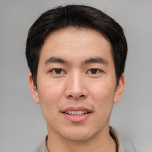Joyful asian young-adult male with short  brown hair and brown eyes