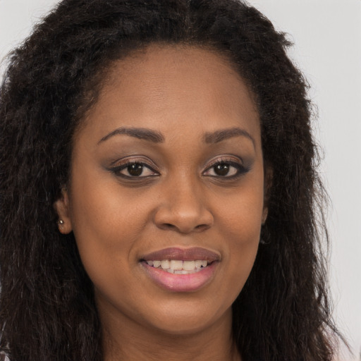 Joyful black young-adult female with long  brown hair and brown eyes