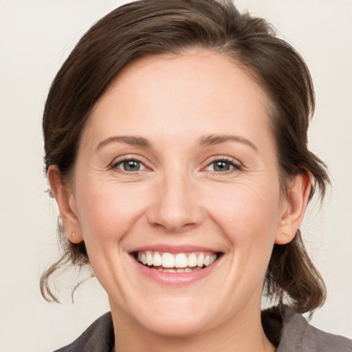 Joyful white young-adult female with medium  brown hair and grey eyes