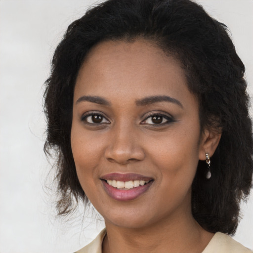 Joyful black young-adult female with long  brown hair and brown eyes