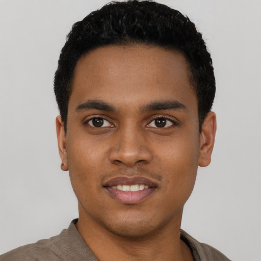 Joyful black young-adult male with short  black hair and brown eyes