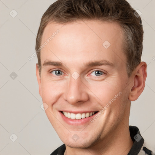 Joyful white young-adult male with short  brown hair and grey eyes