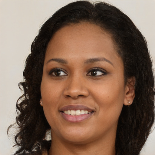 Joyful black young-adult female with long  brown hair and brown eyes