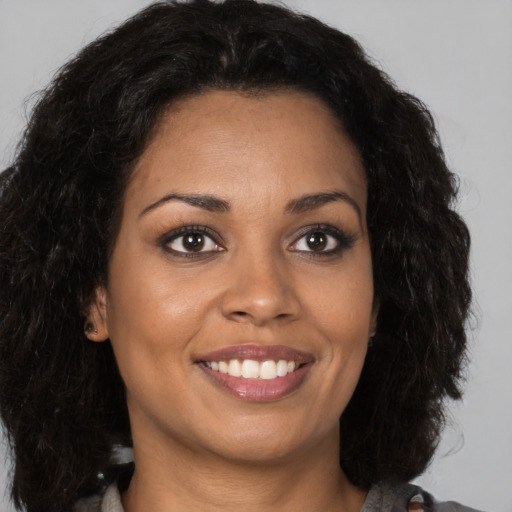 Joyful black young-adult female with long  brown hair and brown eyes