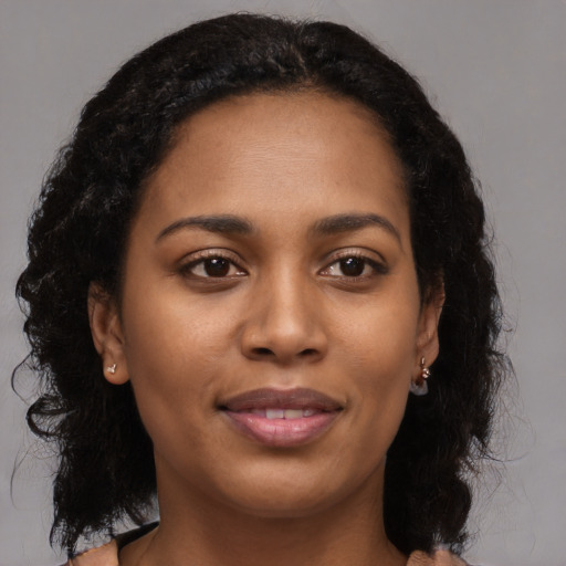 Joyful black young-adult female with long  brown hair and brown eyes