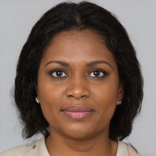 Joyful black young-adult female with long  brown hair and brown eyes