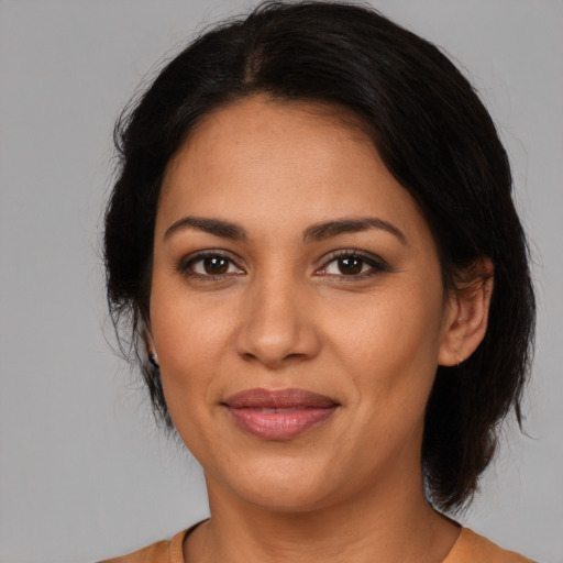 Joyful latino adult female with medium  brown hair and brown eyes