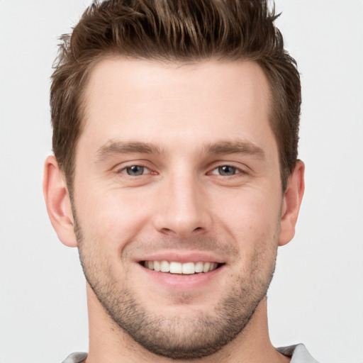 Joyful white young-adult male with short  brown hair and grey eyes