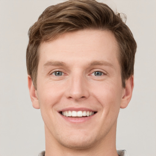 Joyful white young-adult male with short  brown hair and grey eyes