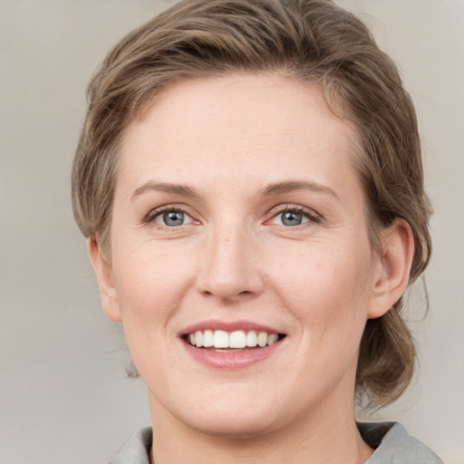 Joyful white young-adult female with medium  brown hair and grey eyes