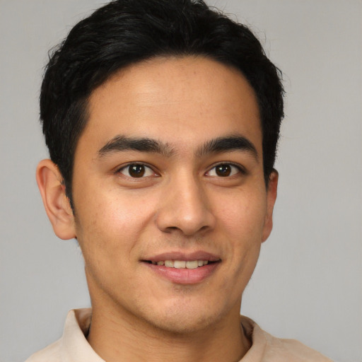 Joyful latino young-adult male with short  brown hair and brown eyes