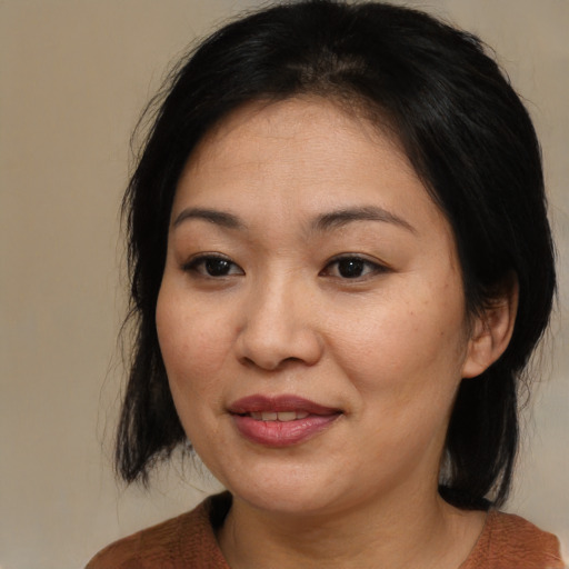 Joyful asian adult female with medium  brown hair and brown eyes