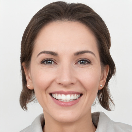 Joyful white young-adult female with medium  brown hair and grey eyes