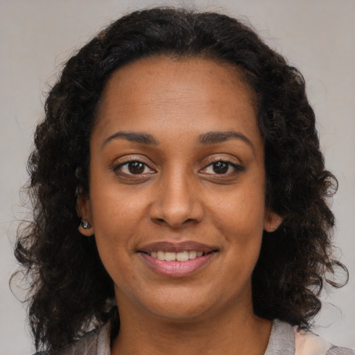 Joyful black young-adult female with long  brown hair and brown eyes