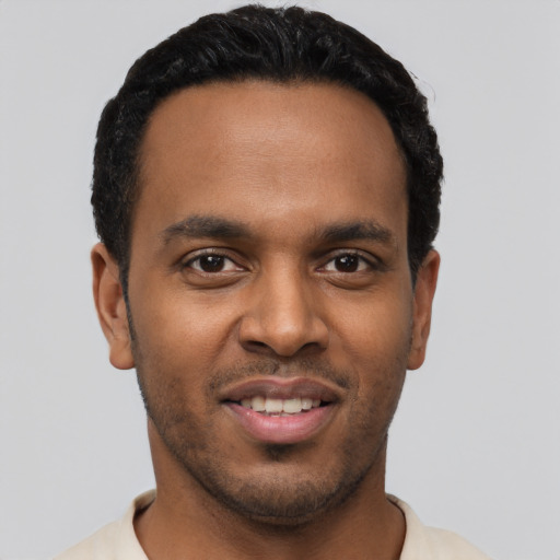 Joyful black young-adult male with short  brown hair and brown eyes