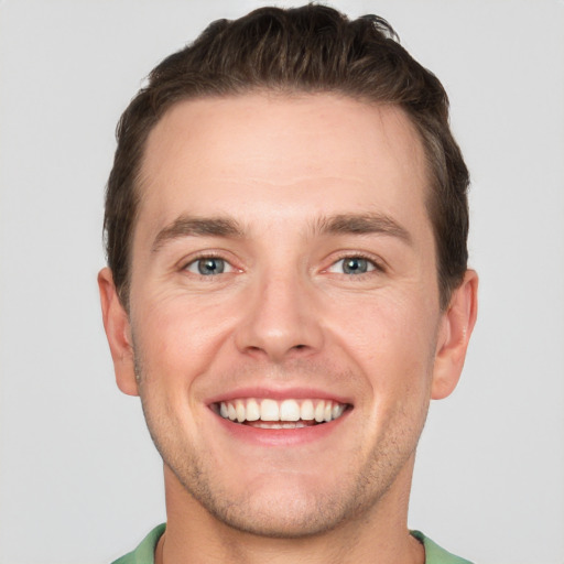 Joyful white young-adult male with short  brown hair and grey eyes