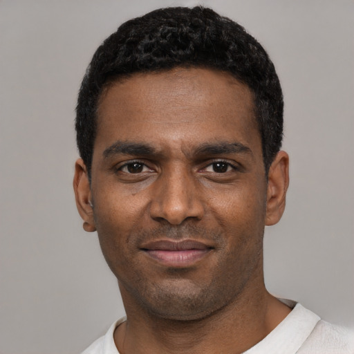 Joyful black young-adult male with short  black hair and brown eyes
