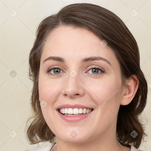 Joyful white young-adult female with medium  brown hair and green eyes