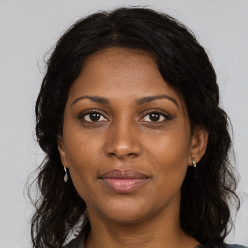 Joyful black young-adult female with long  brown hair and brown eyes