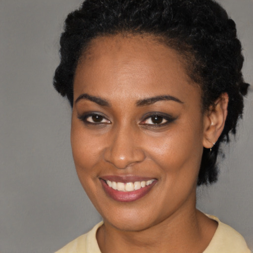 Joyful black young-adult female with short  black hair and brown eyes