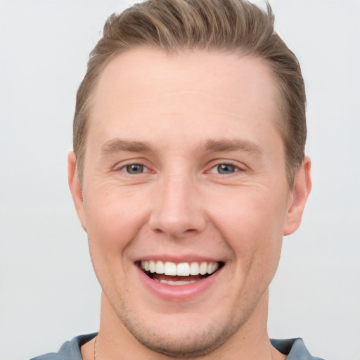 Joyful white young-adult male with short  brown hair and grey eyes