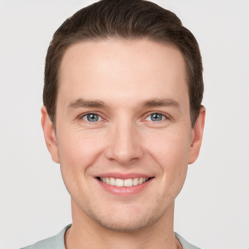 Joyful white young-adult male with short  brown hair and grey eyes