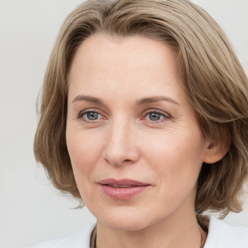 Joyful white adult female with medium  brown hair and grey eyes