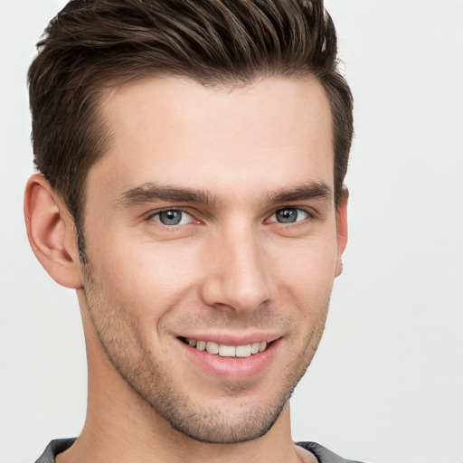 Joyful white young-adult male with short  brown hair and grey eyes