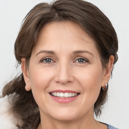 Joyful white adult female with medium  brown hair and grey eyes