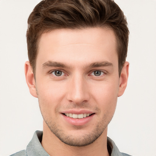 Joyful white young-adult male with short  brown hair and grey eyes