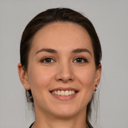 Joyful white young-adult female with medium  brown hair and grey eyes