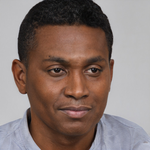 Joyful black young-adult male with short  brown hair and brown eyes