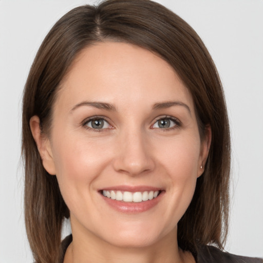 Joyful white young-adult female with medium  brown hair and grey eyes