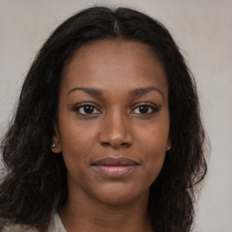 Joyful black young-adult female with long  brown hair and brown eyes