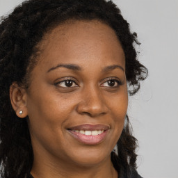 Joyful black young-adult female with long  brown hair and brown eyes