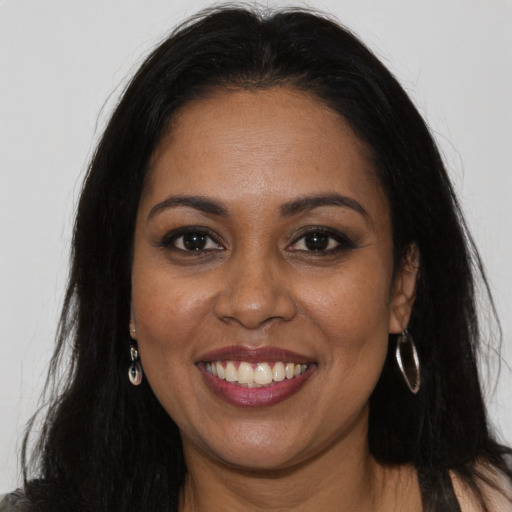 Joyful black young-adult female with long  brown hair and brown eyes