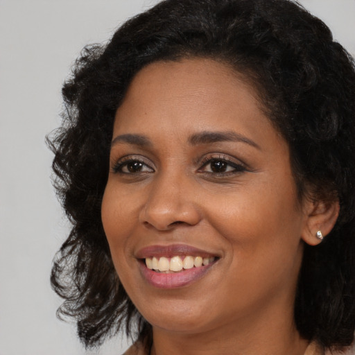 Joyful black young-adult female with long  brown hair and brown eyes