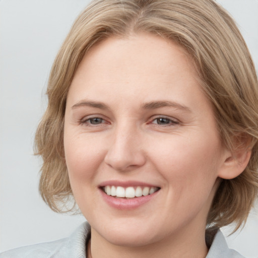 Joyful white young-adult female with medium  brown hair and blue eyes