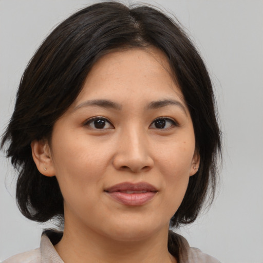 Joyful asian adult female with medium  brown hair and brown eyes