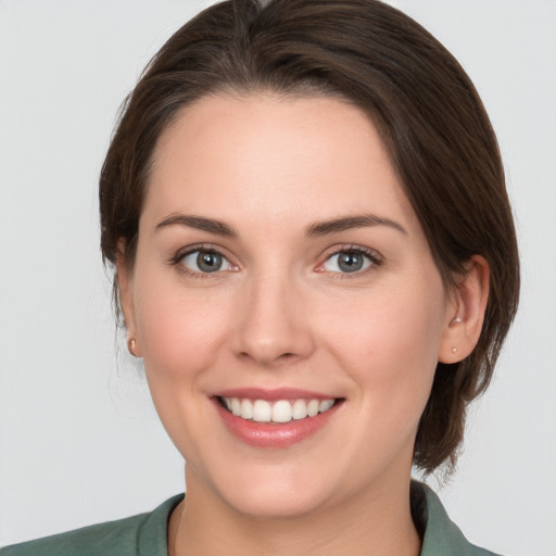 Joyful white young-adult female with medium  brown hair and grey eyes