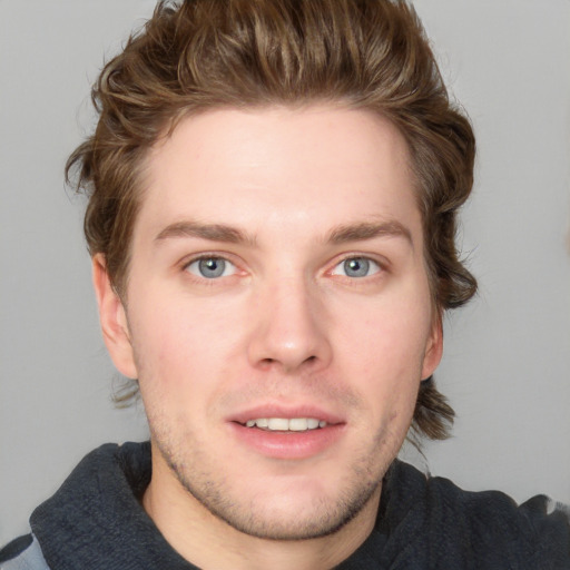 Joyful white young-adult male with short  brown hair and blue eyes